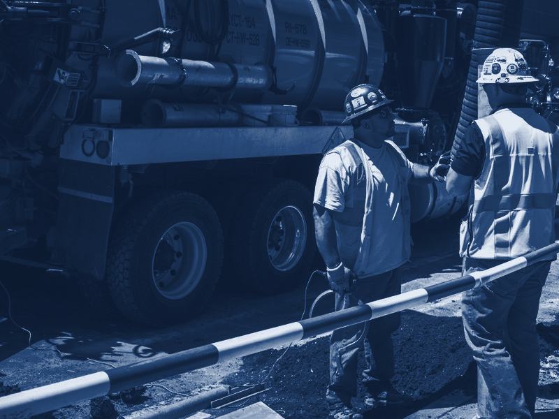 Two septic crew members talking beside a vacuum truck